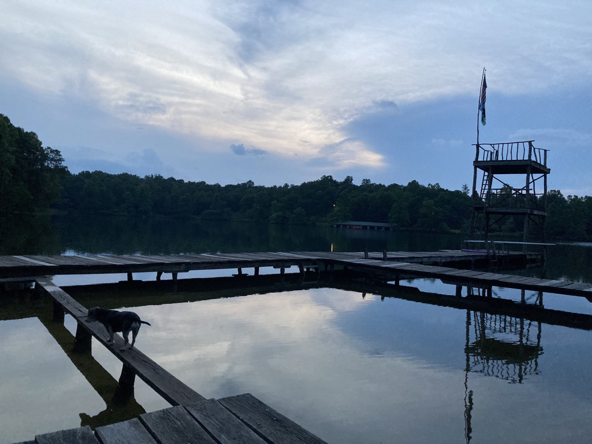 Night falls over a river wear a dock is.